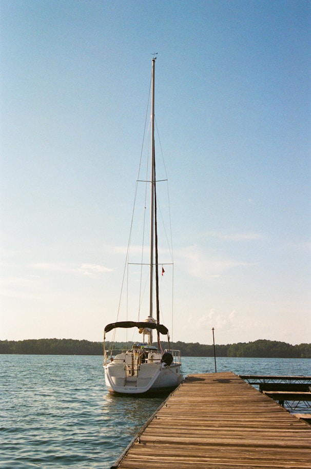 A sailboat is docked at the end of a pier.