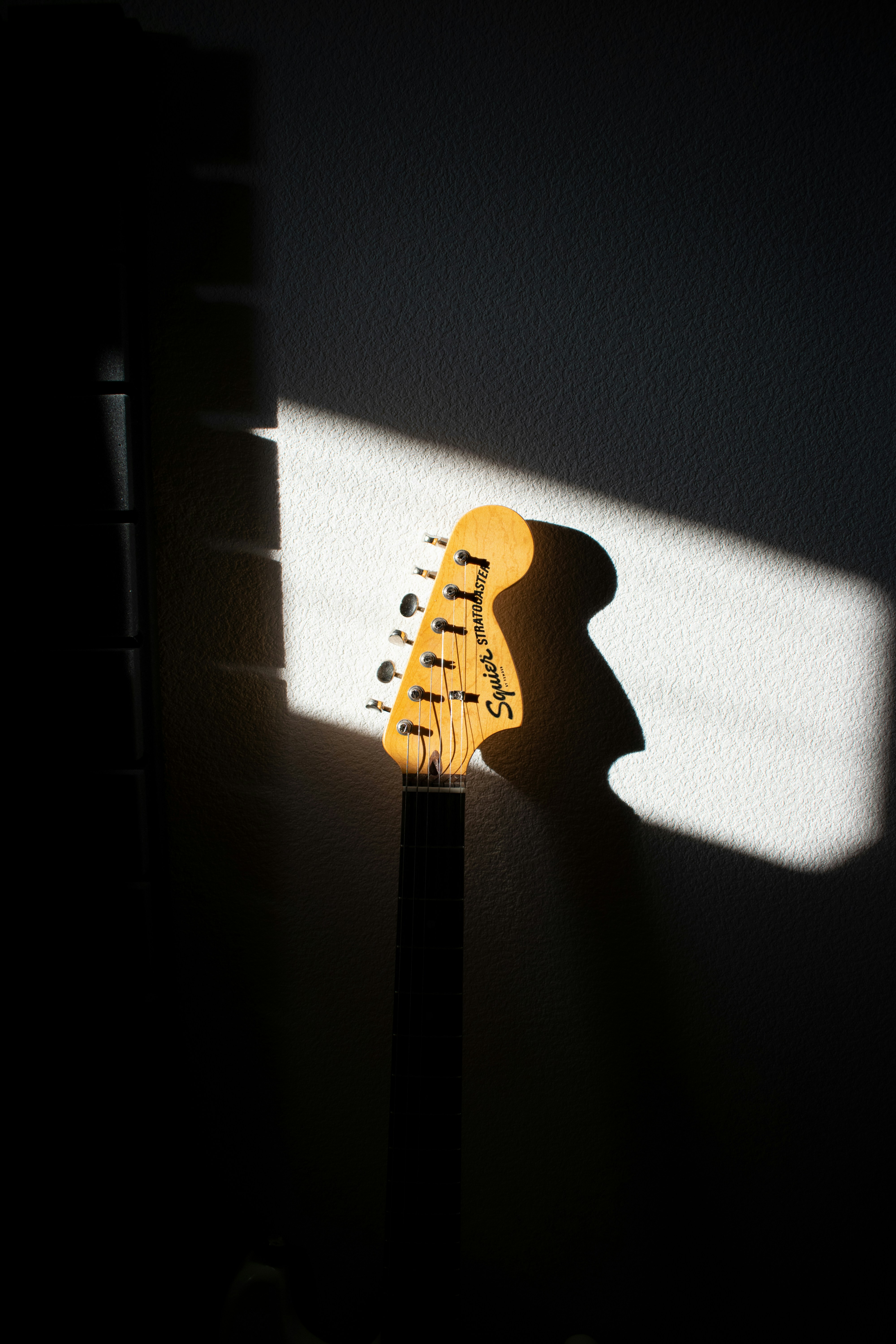 Headstock gitar di bawah sinar matahari yang dramatis.