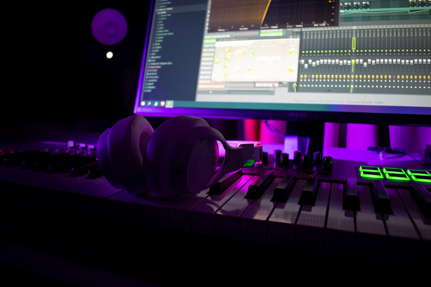 Headphones resting on a music production keyboard in a neon-lit studio
