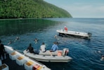 People are swimming in the ocean near boats.