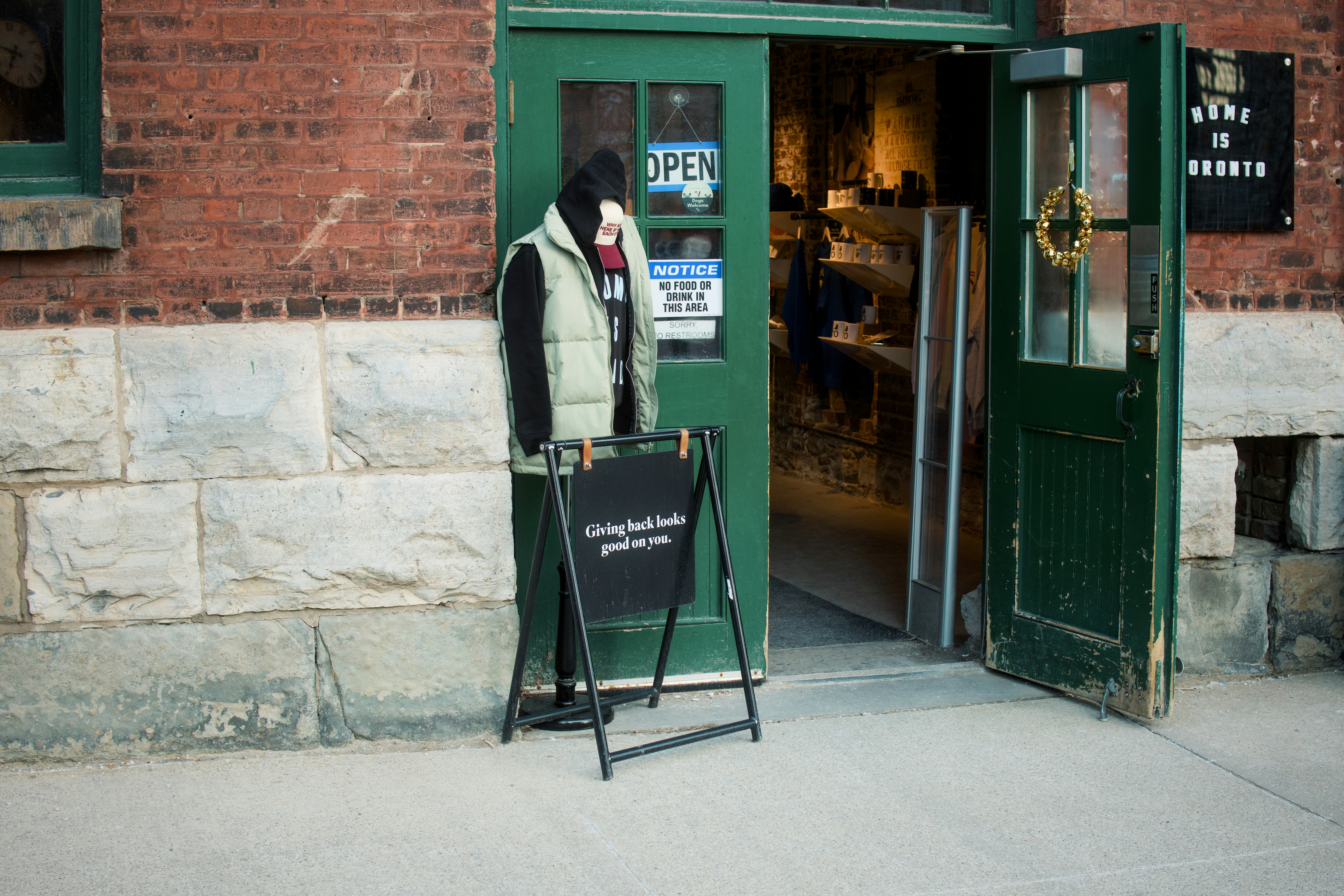 Store entrance with open door and mannequin outside.