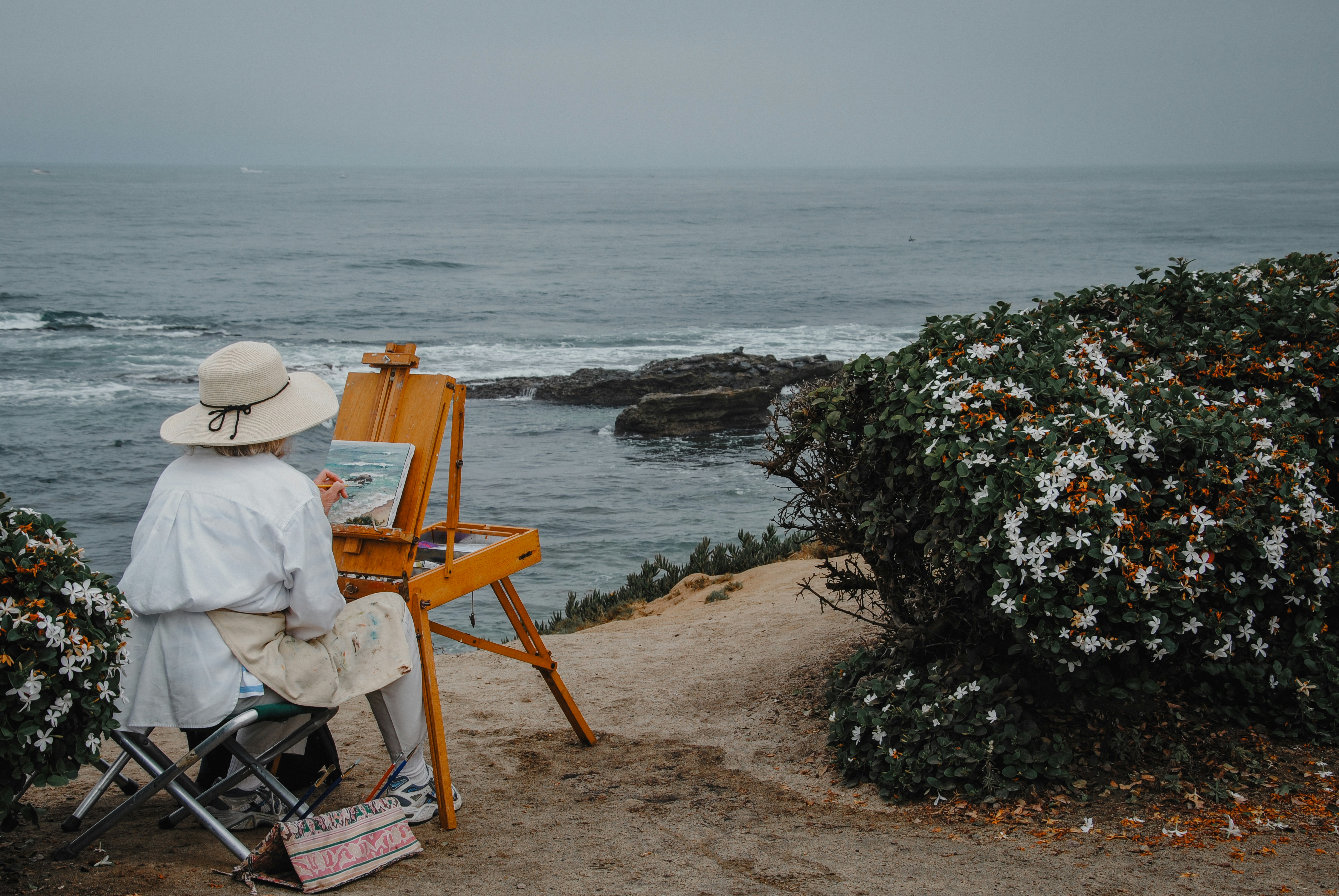 An artist paints a seascape by the ocean.