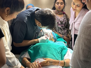 Doctor performs procedure on patient with observers.
