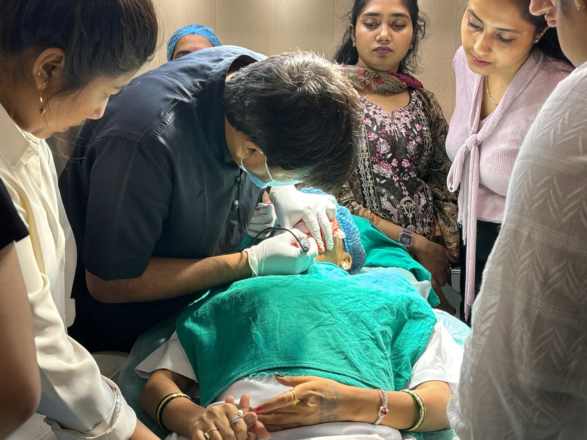 Doctor performs procedure on patient with observers.