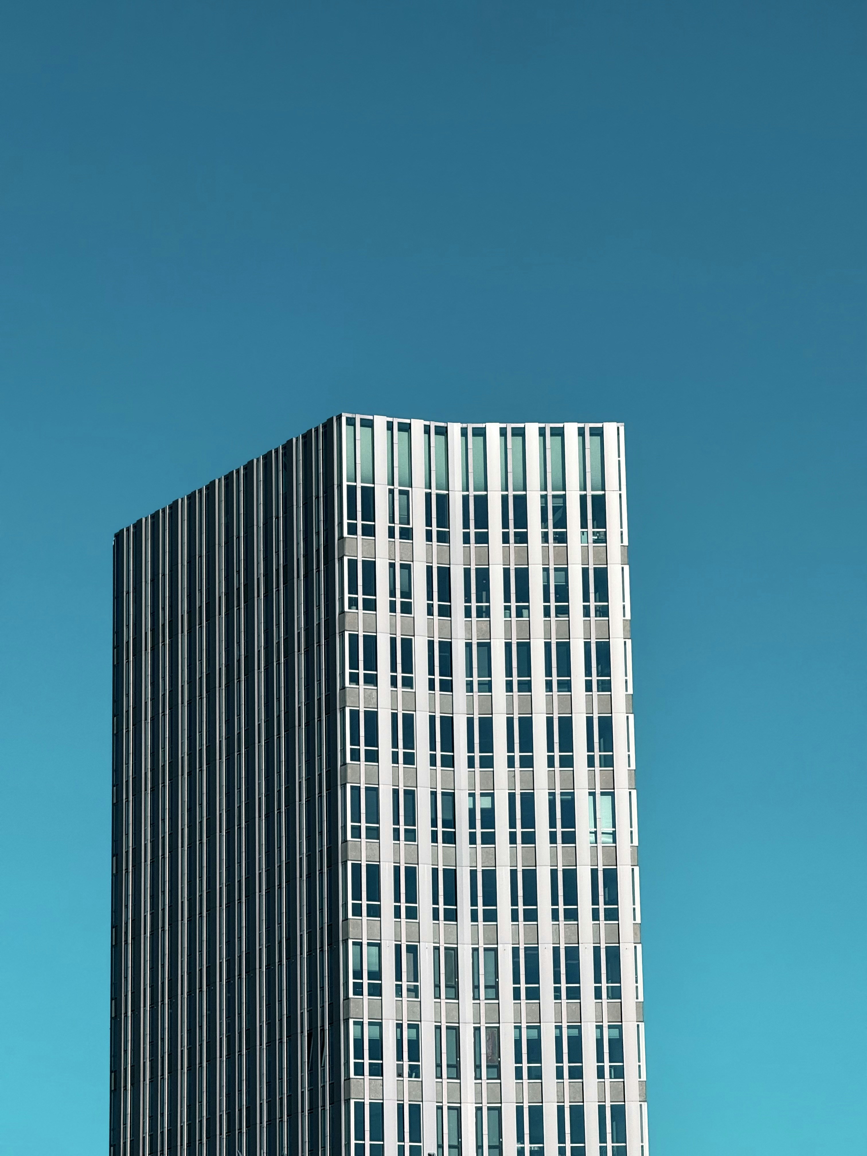 Tall building stands against a vibrant blue sky.