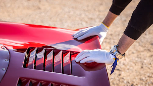 Hands are inspecting a red car's details.