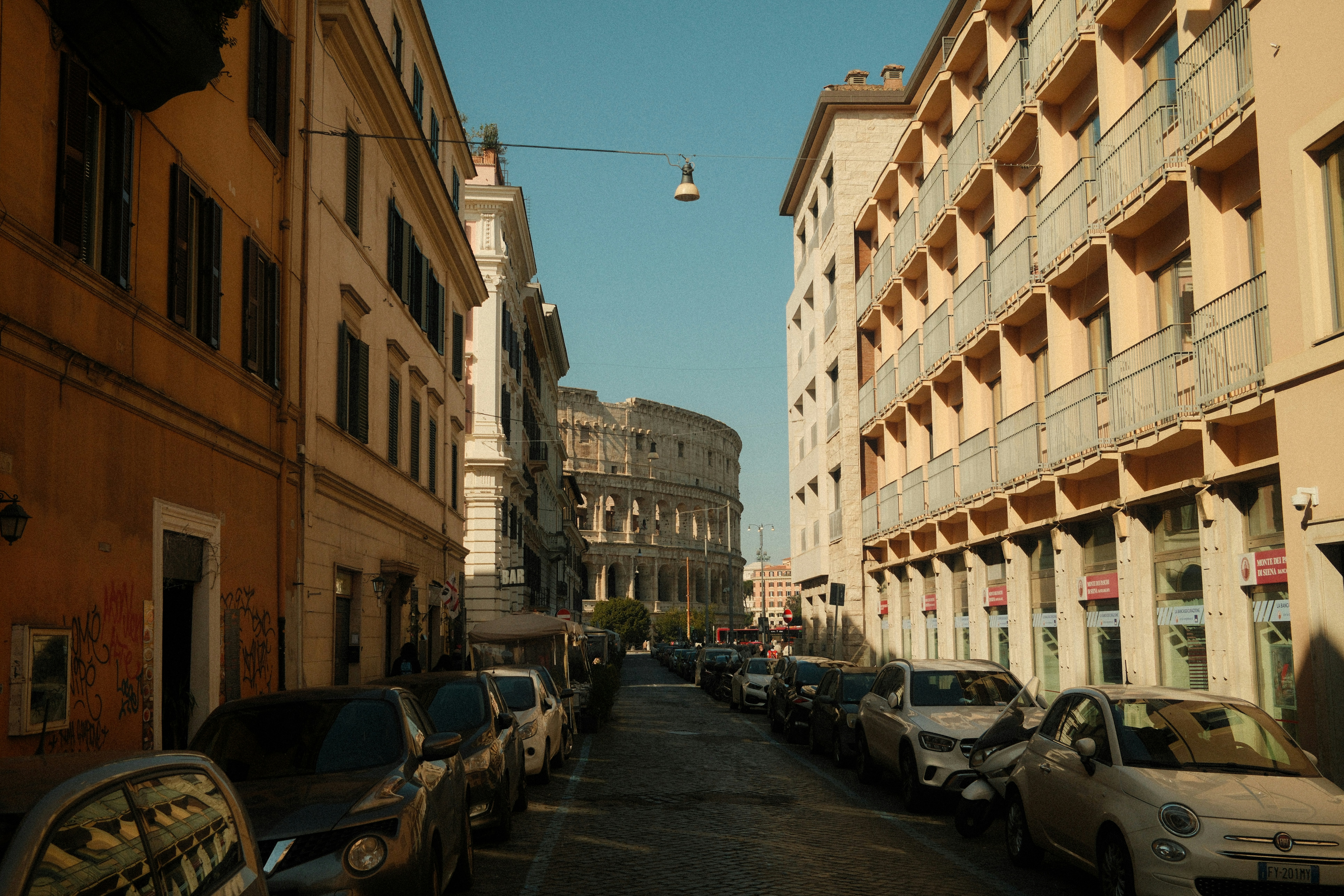 The colosseum is seen down a narrow street., 