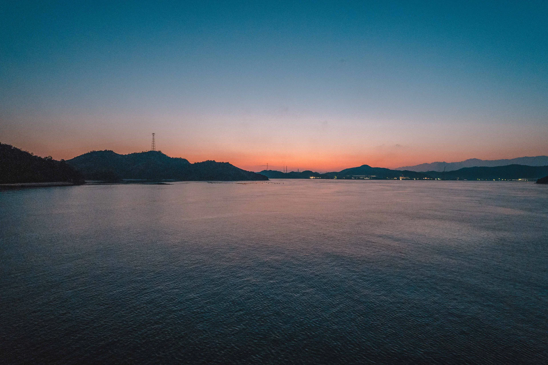 Calm sea at dusk with island silhouettes on the horizon