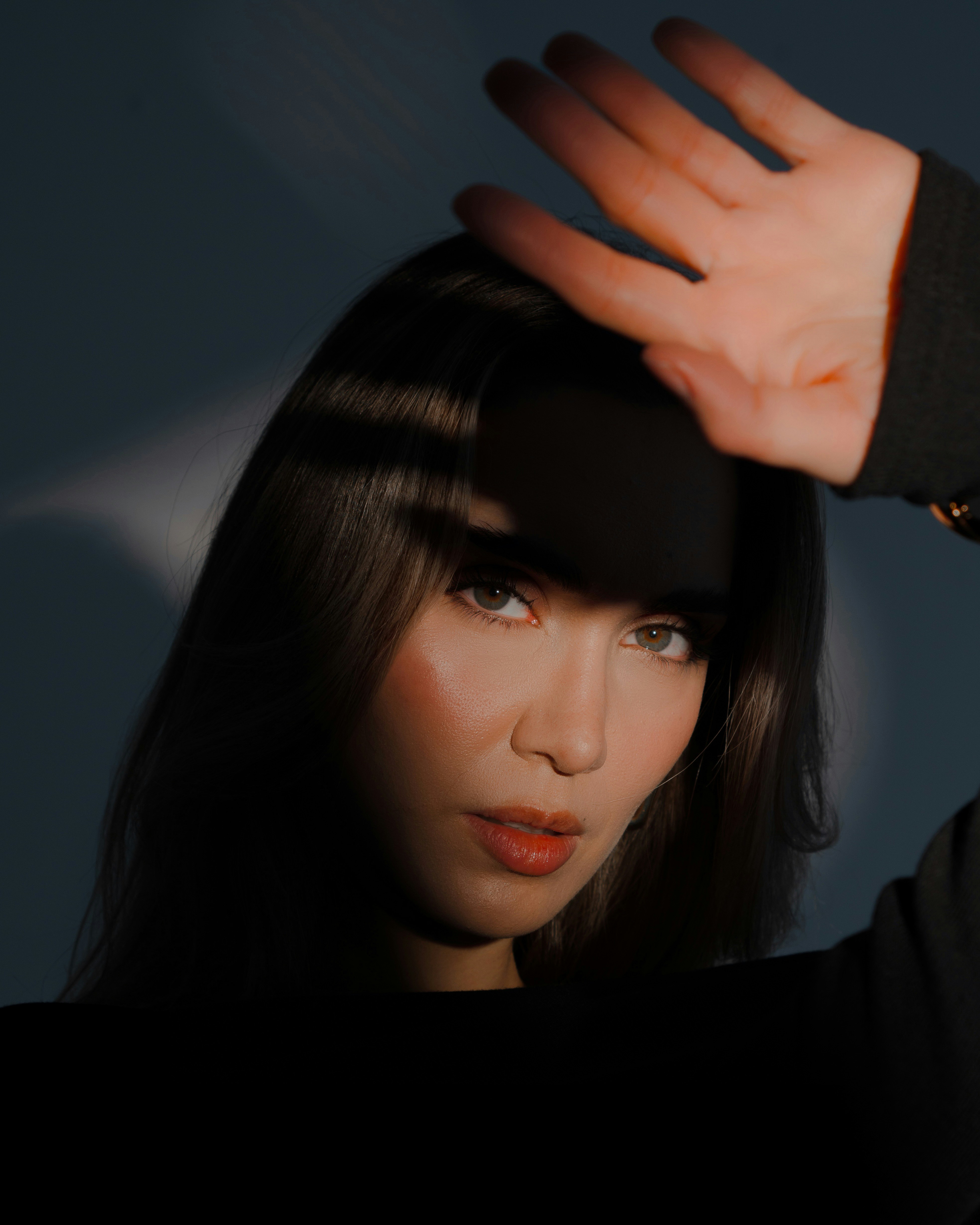 Woman poses, shielding her eyes from the light.