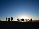 People gather outdoors, watching the sunset.