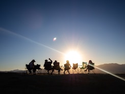 Friends enjoy sunset while camping outside.