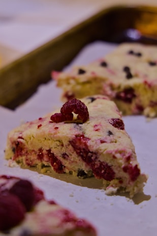 Fresh raspberry scones sit on parchment paper.