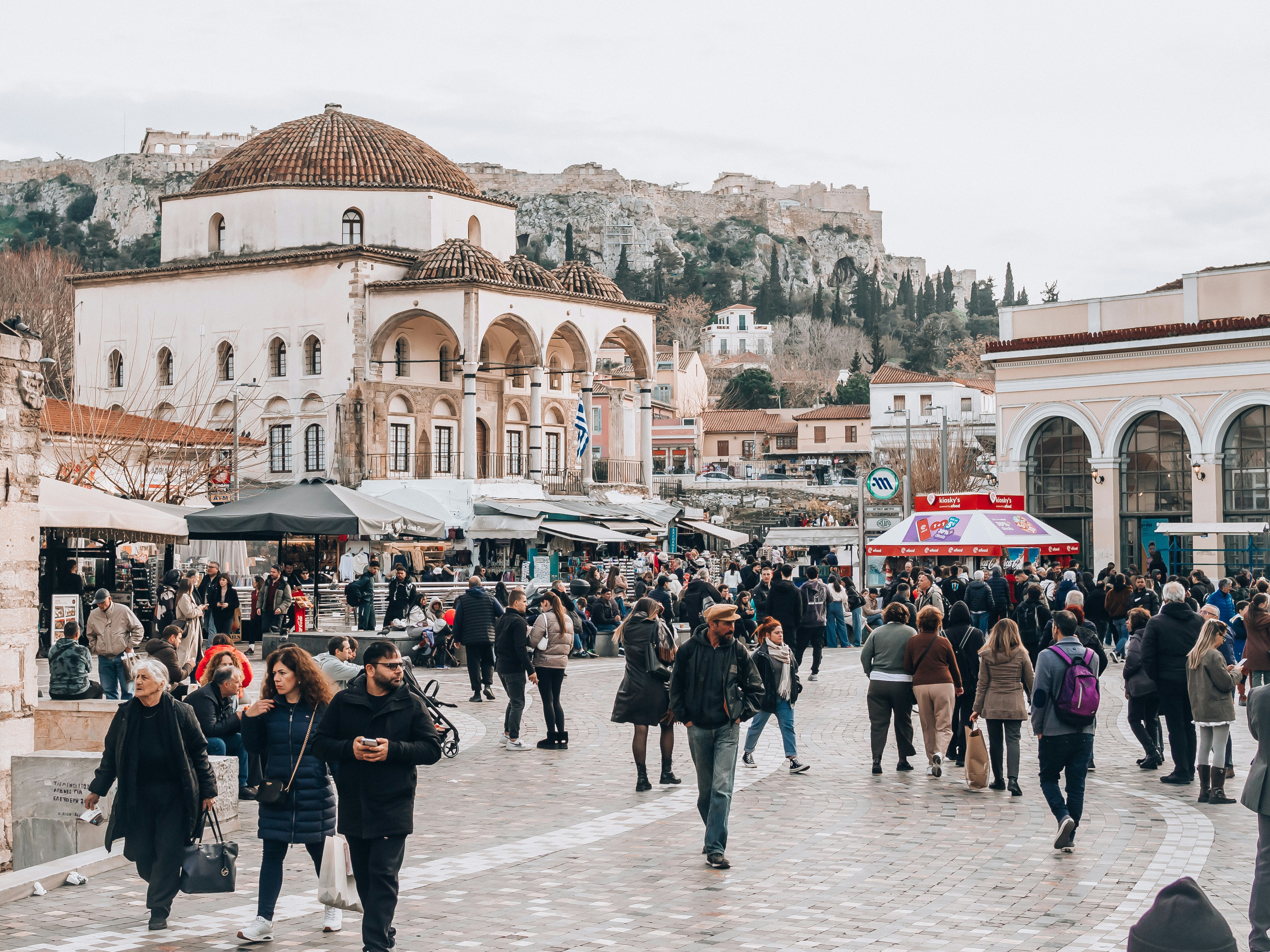 People walk through a market square in athens.