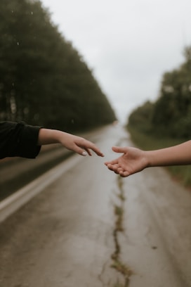Reaching hands on a rainy road symbolize connection.