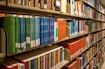 Bookshelves are filled with colorful books in a library.