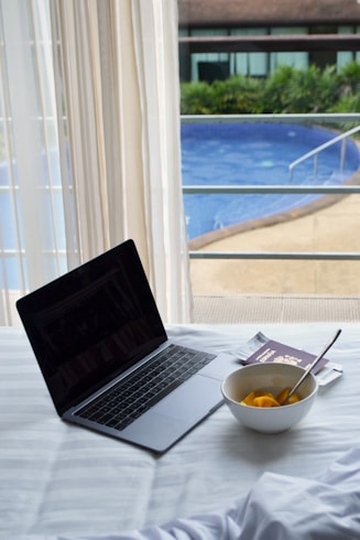 Laptop, fruit, and passport beside a pool.