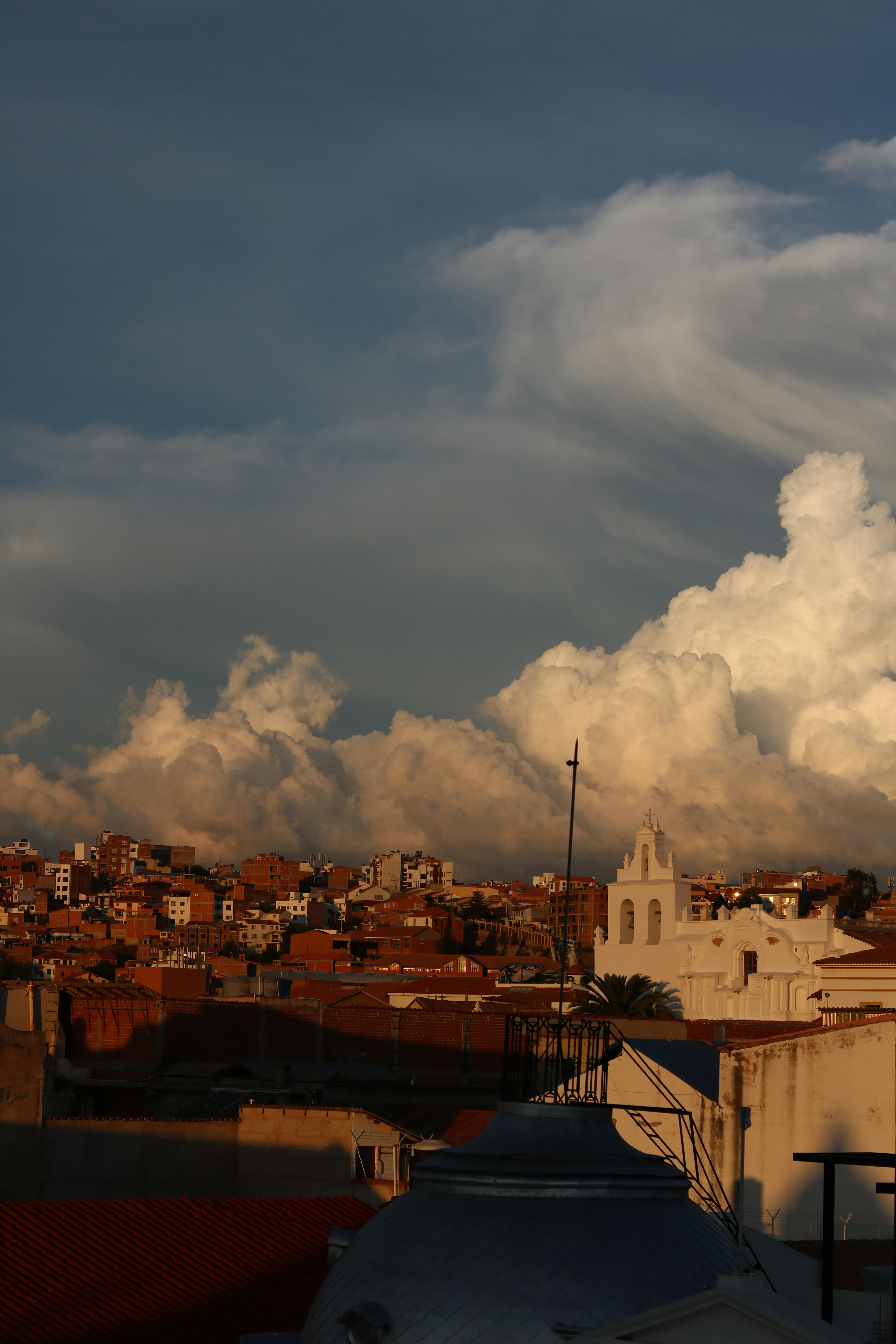 Cityscape under dramatic storm clouds at sunset.