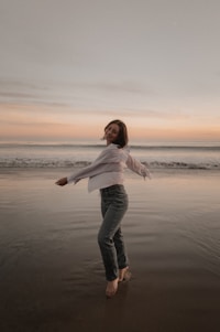 Woman happily spins on a beach at sunset.