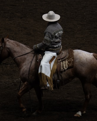A cowboy rides a horse in a rodeo arena.