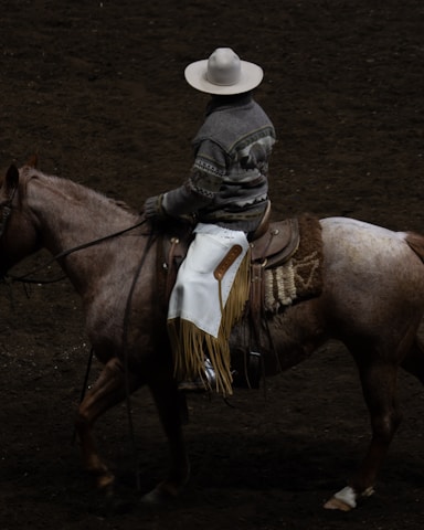 A cowboy rides a horse in a rodeo arena.