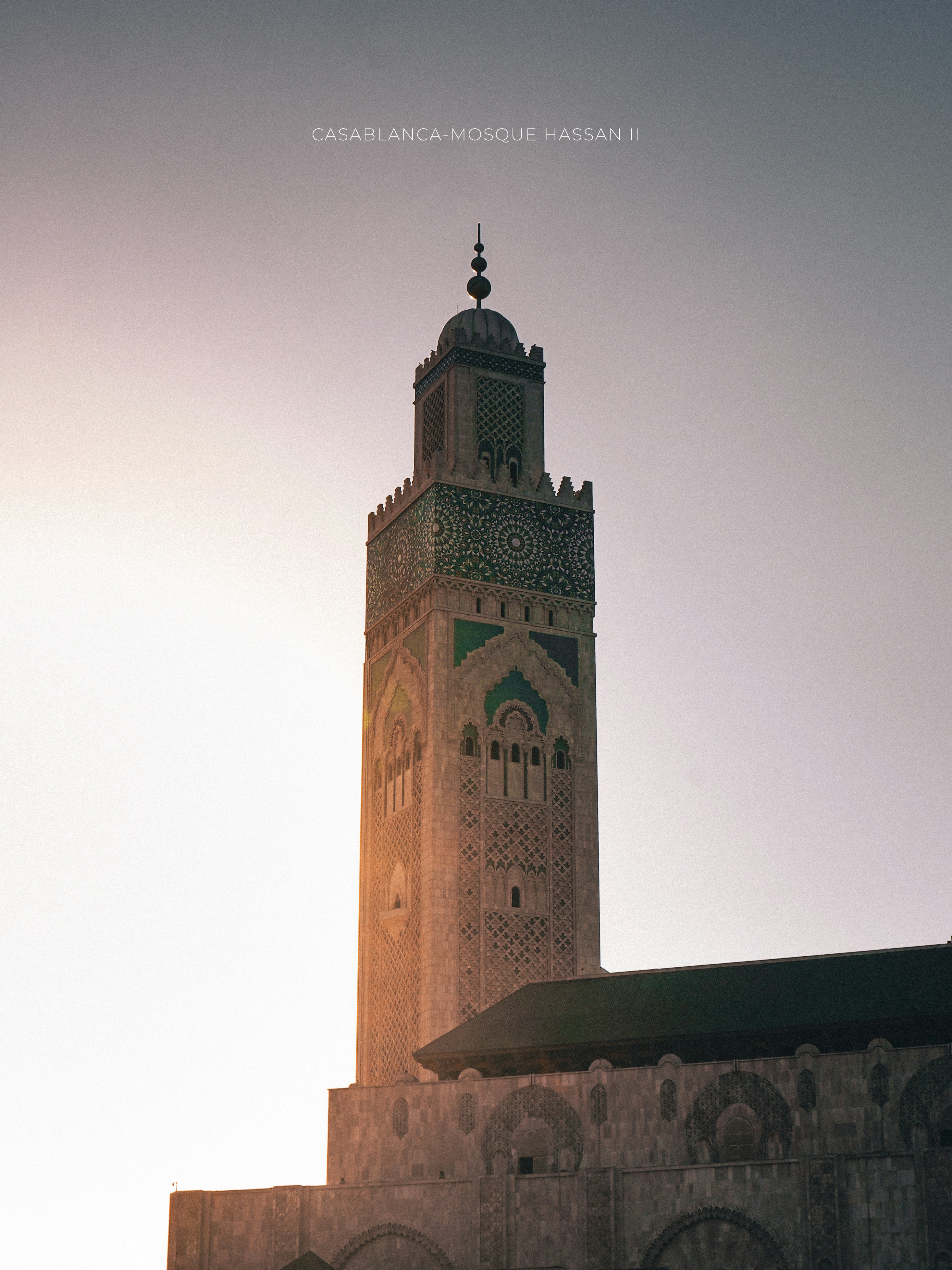 The hassan ii mosque tower stands tall at sunset.