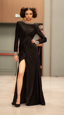 A model poses in a black dress with a slit.