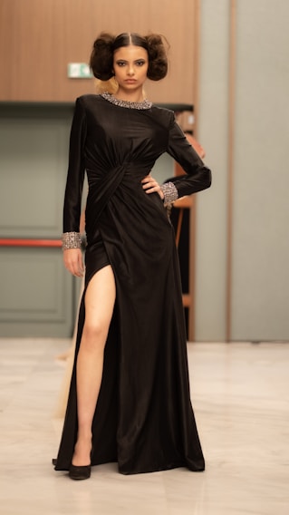 A model poses in a black dress with a slit.