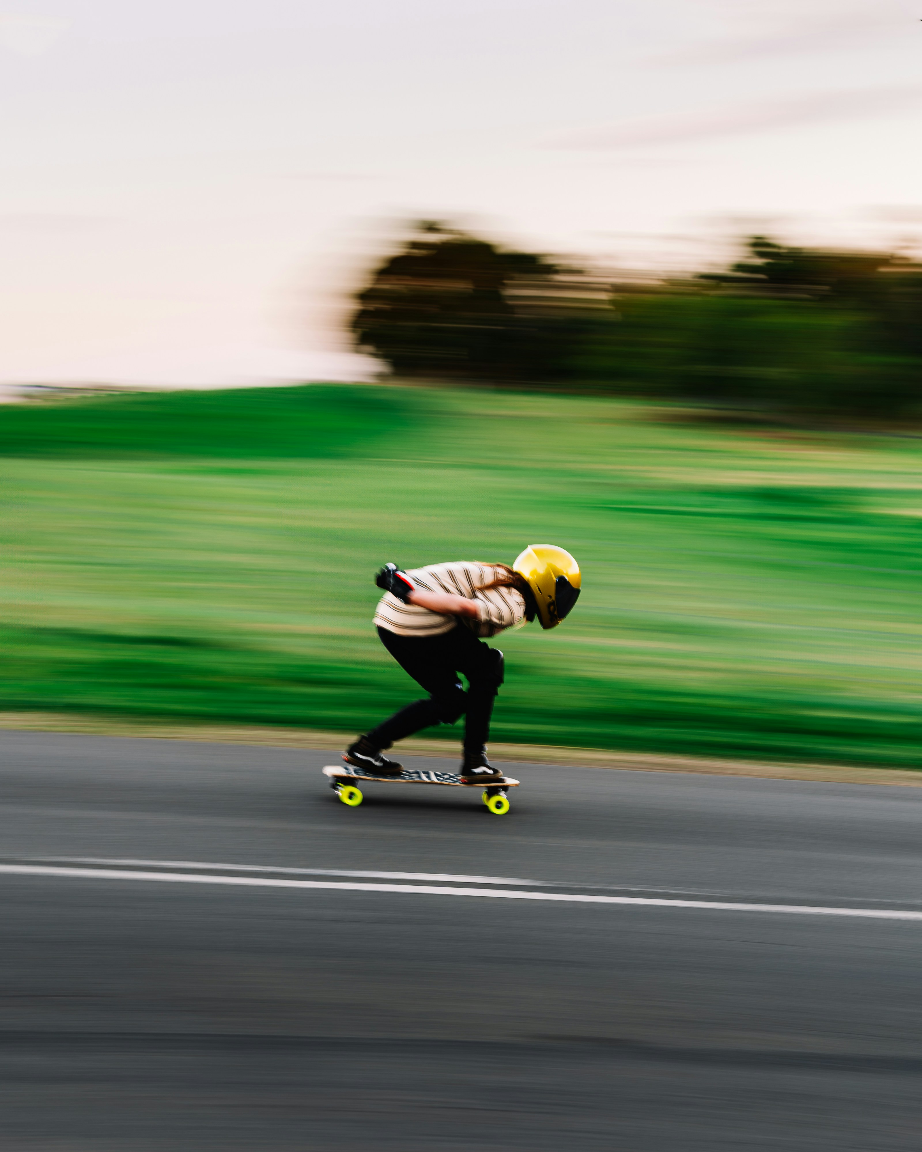 Person rides a skateboard down a road at speed.