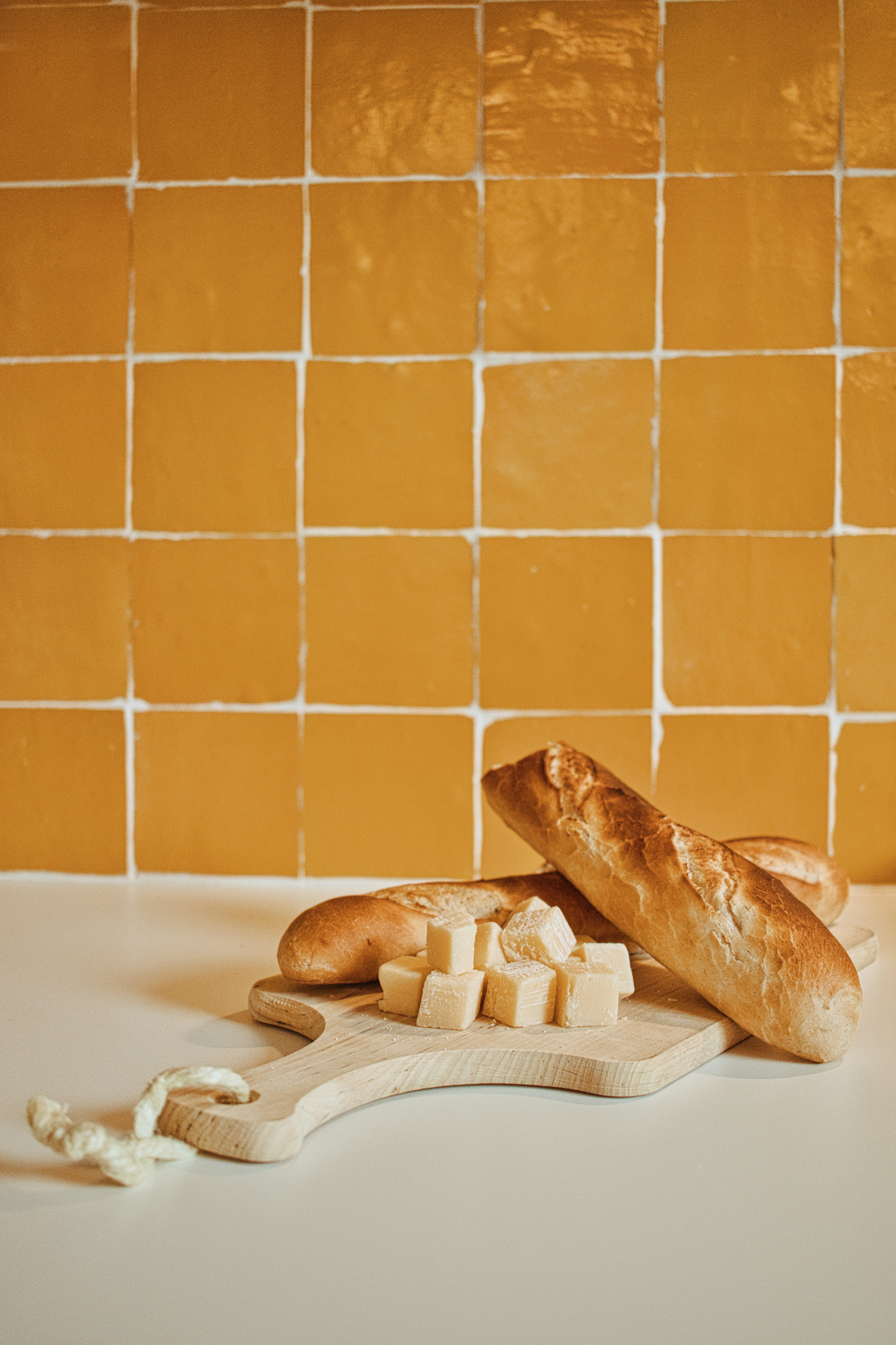 Bread and cheese sit on a wooden cutting board.