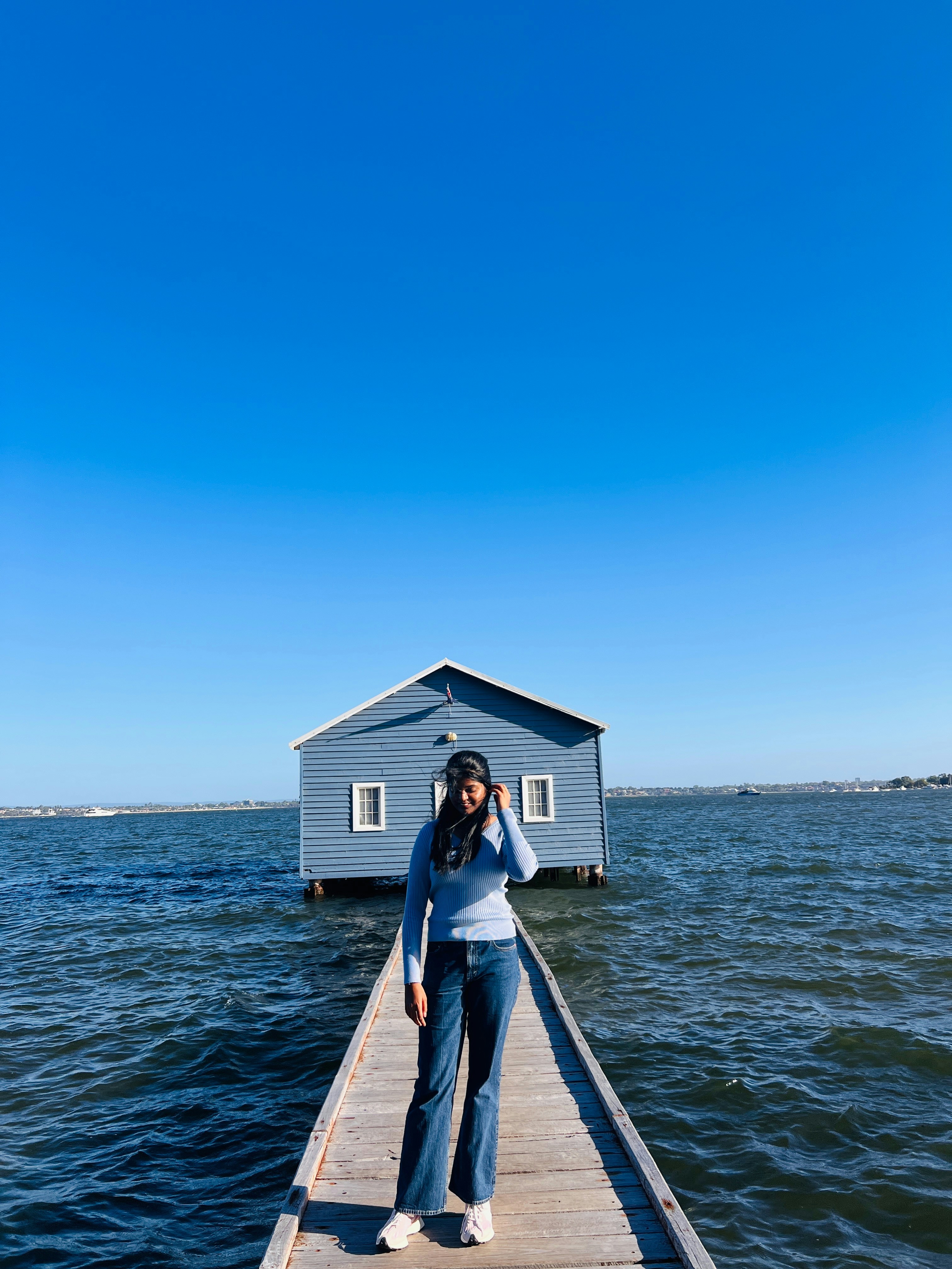 Frau posiert auf einem Pier mit dem blauen Bootshaus.