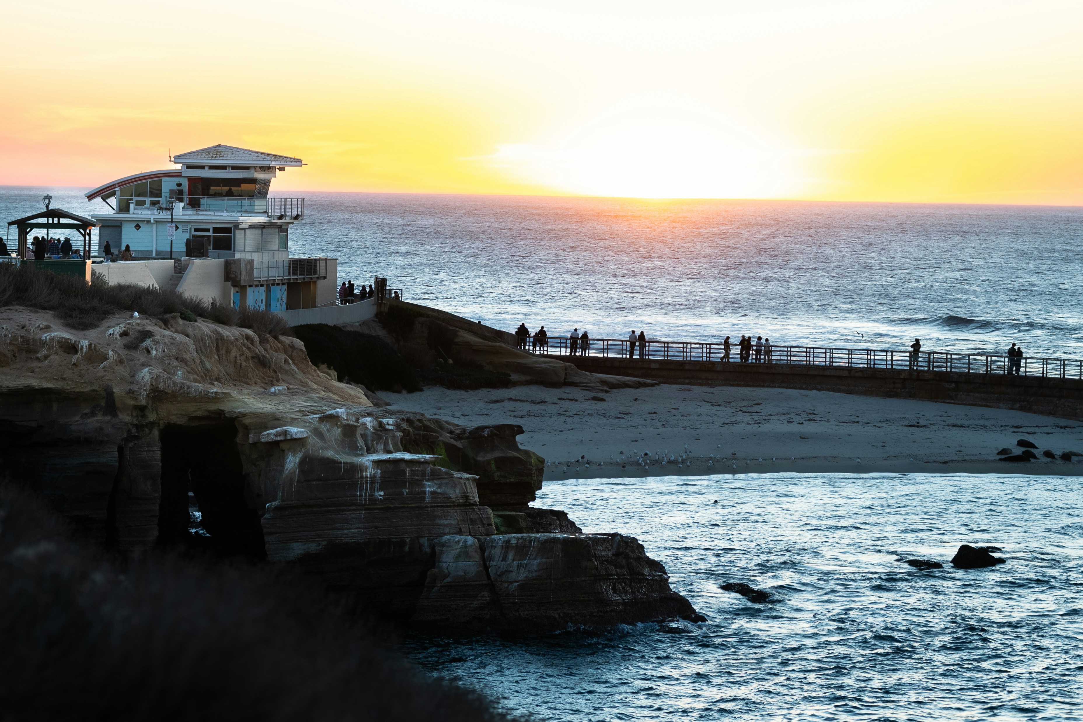 Sunset over the ocean with a building.