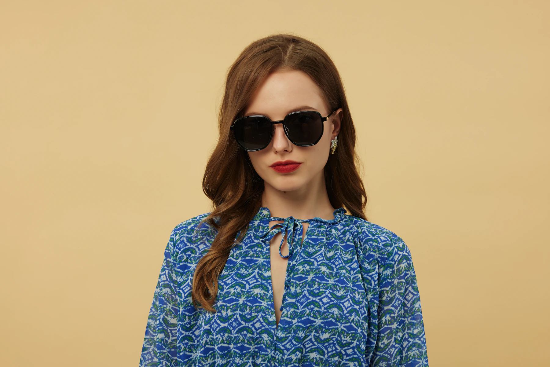 Woman wearing oversized black sunglasses and a blue patterned dress