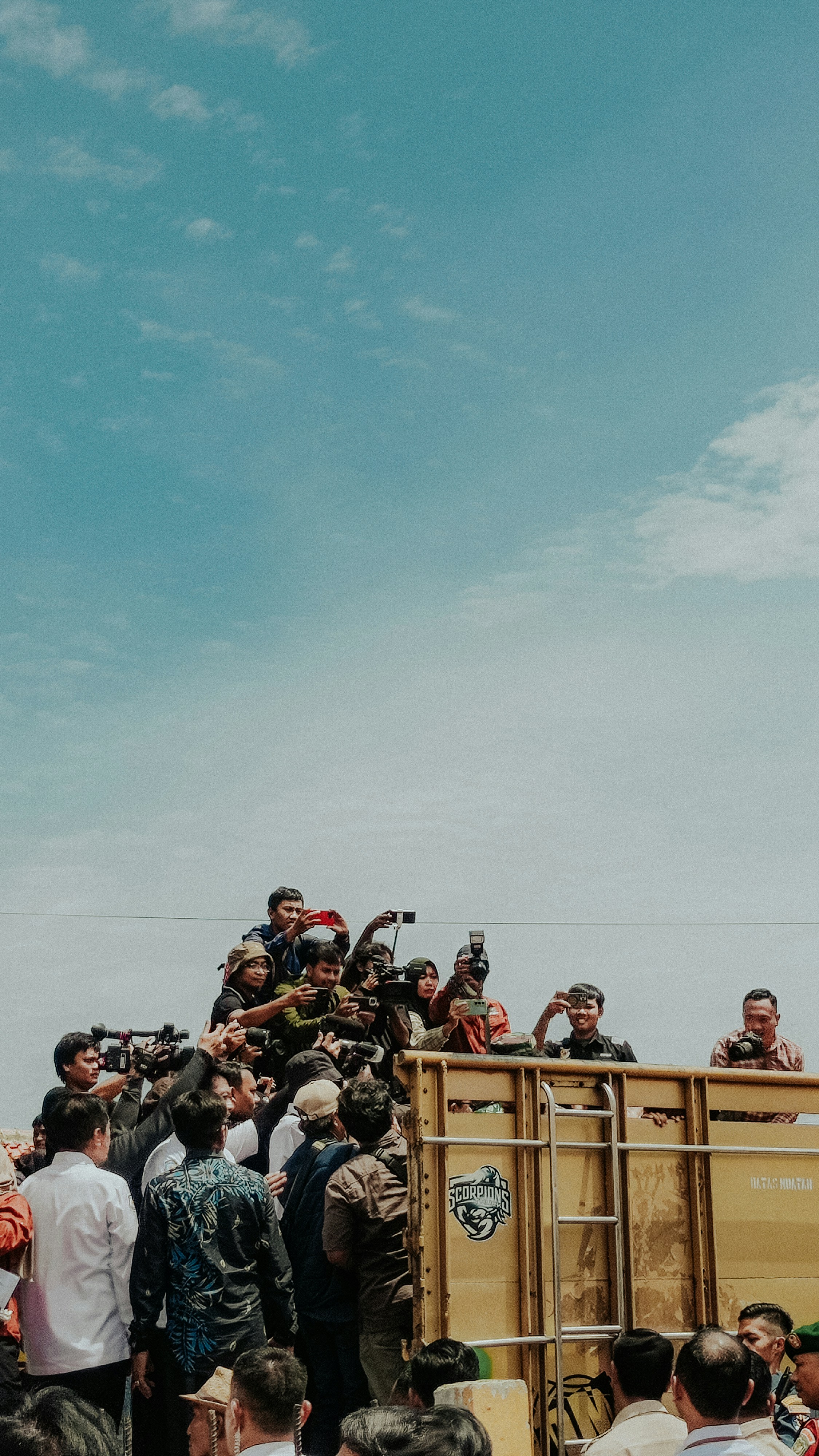 Journalists and people surrounded a flatbed truck.