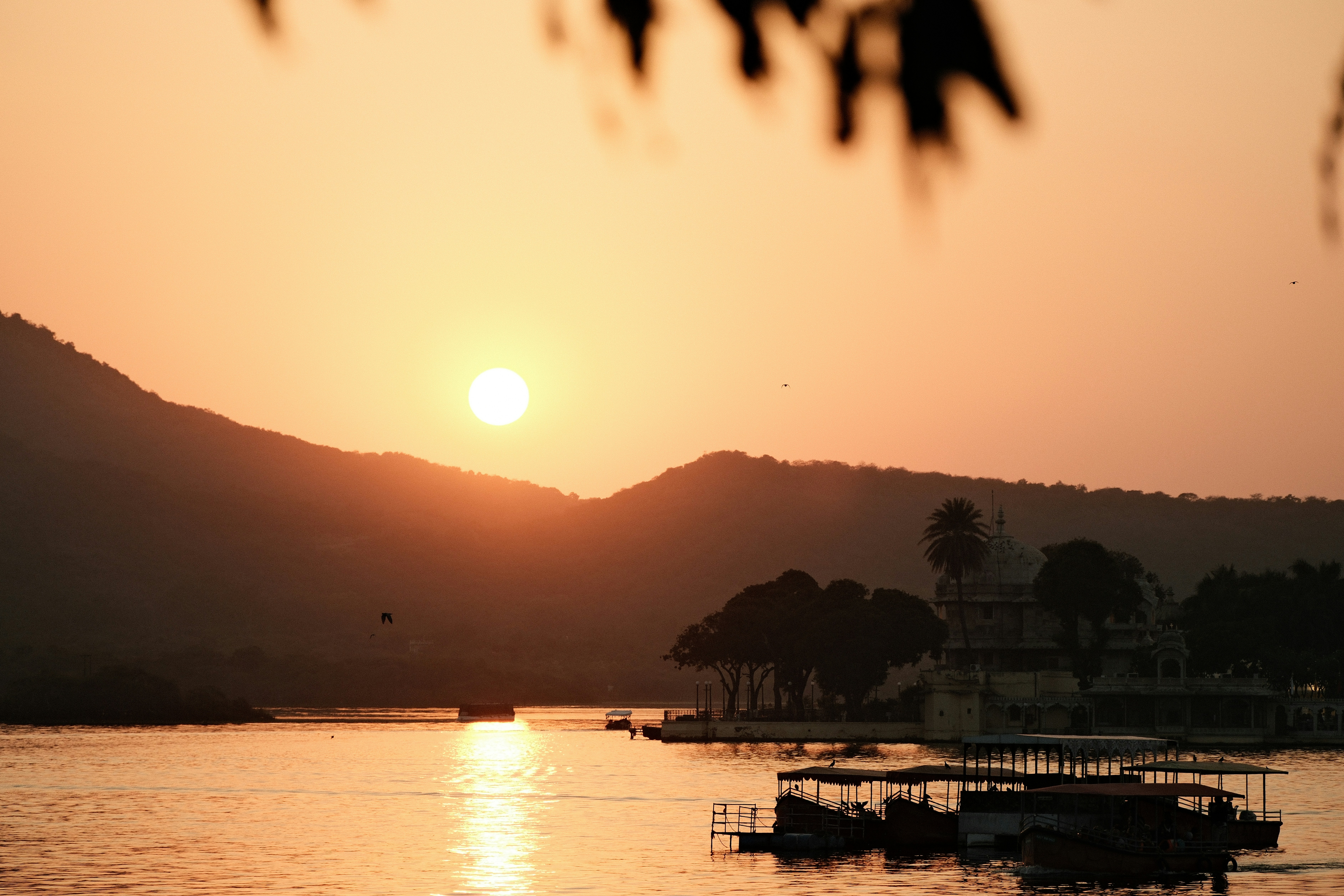 Sunset over a lake with mountains and boats.