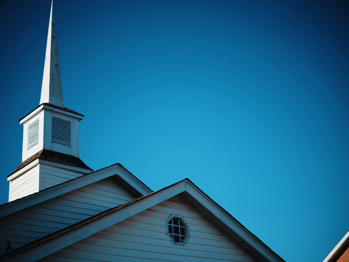 A white church steeple against a blue sky