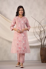 Woman poses in a pink floral kurta and pants.
