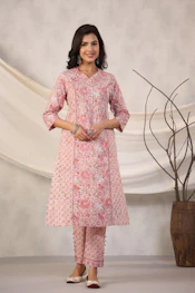 Woman poses in a pink floral kurta and pants.