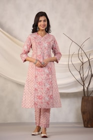Woman poses in a pink floral kurta and pants.