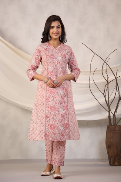 Woman poses in a pink floral kurta and pants.