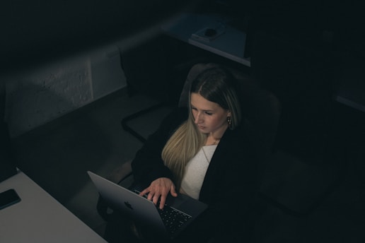 Woman working late on a laptop in a dark office.