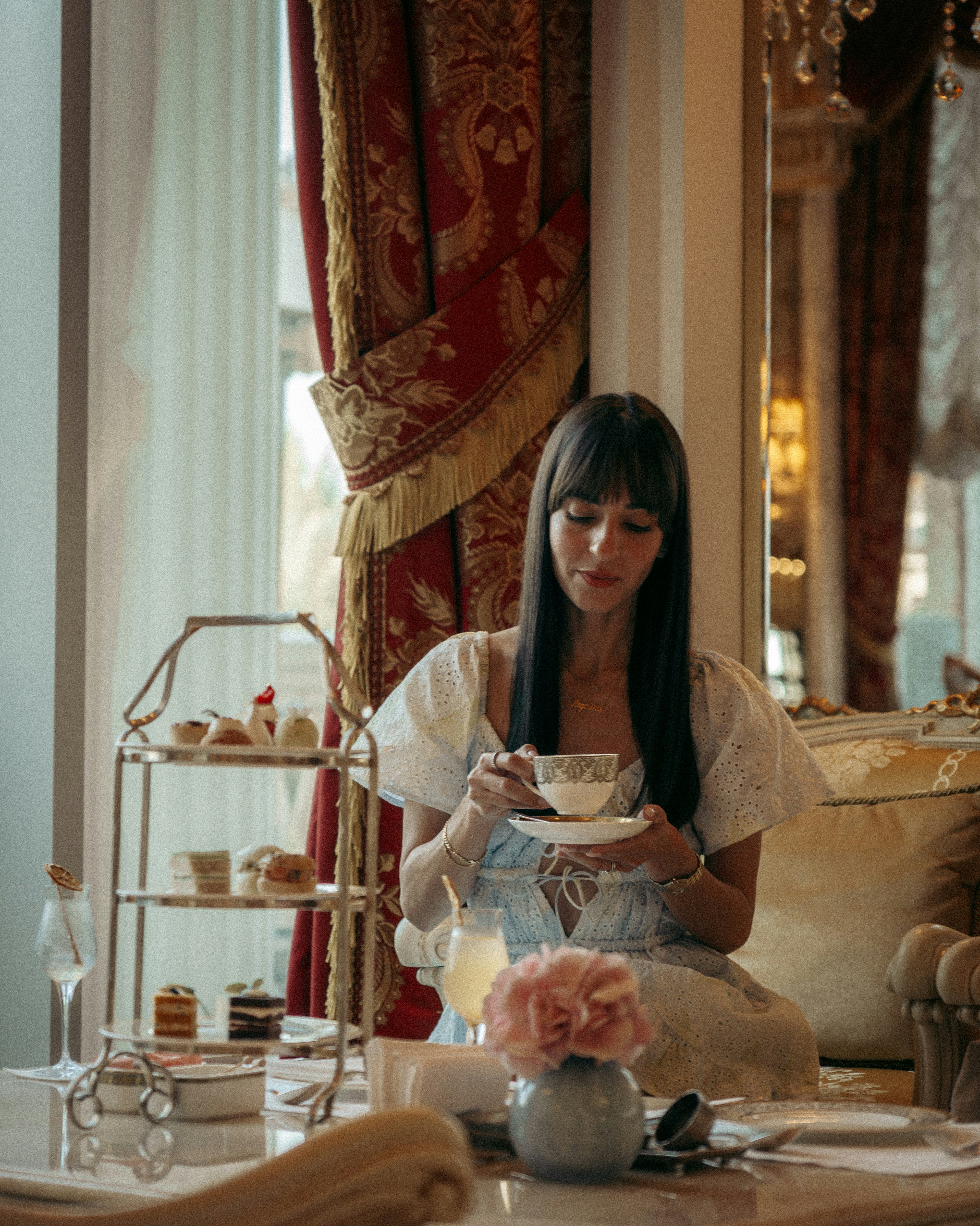 Woman enjoys high tea in a luxurious setting.