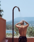 Man enjoys an outdoor shower with scenic views.