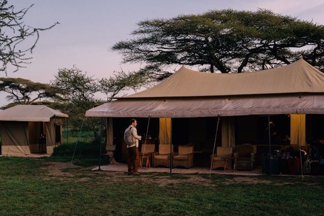 Person standing near a tent in an african safari.