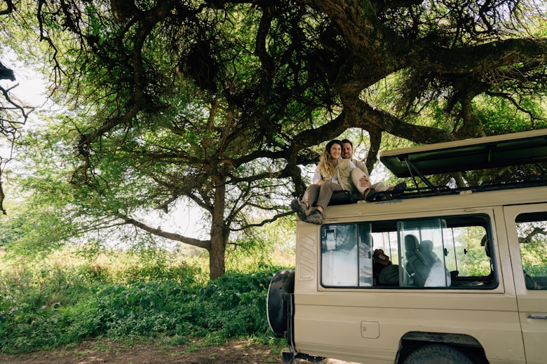 People are sitting on top of a safari vehicle.