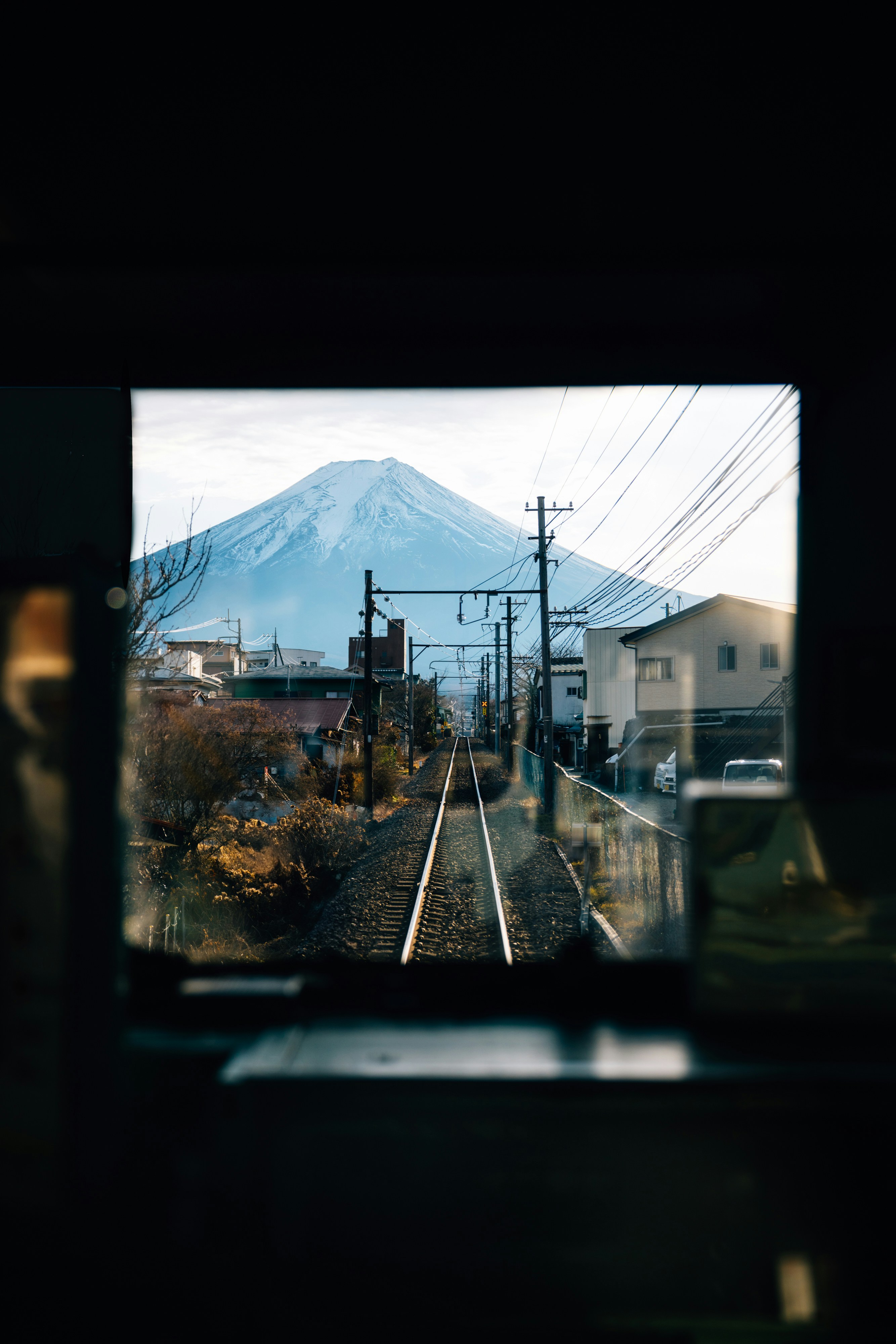 Train tracks lead to a view of mount fuji.