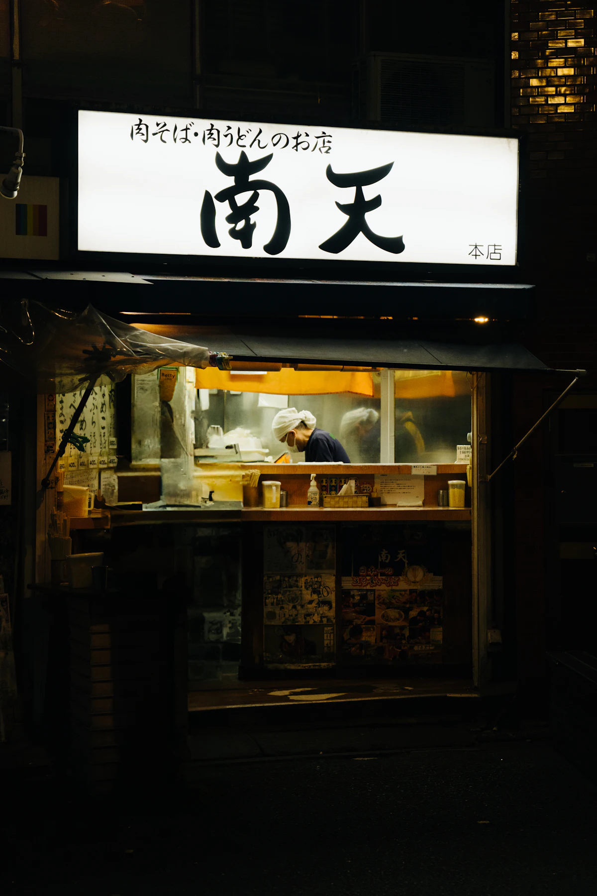 A Japanese noodle shop glowing under lanterns, open late at night
