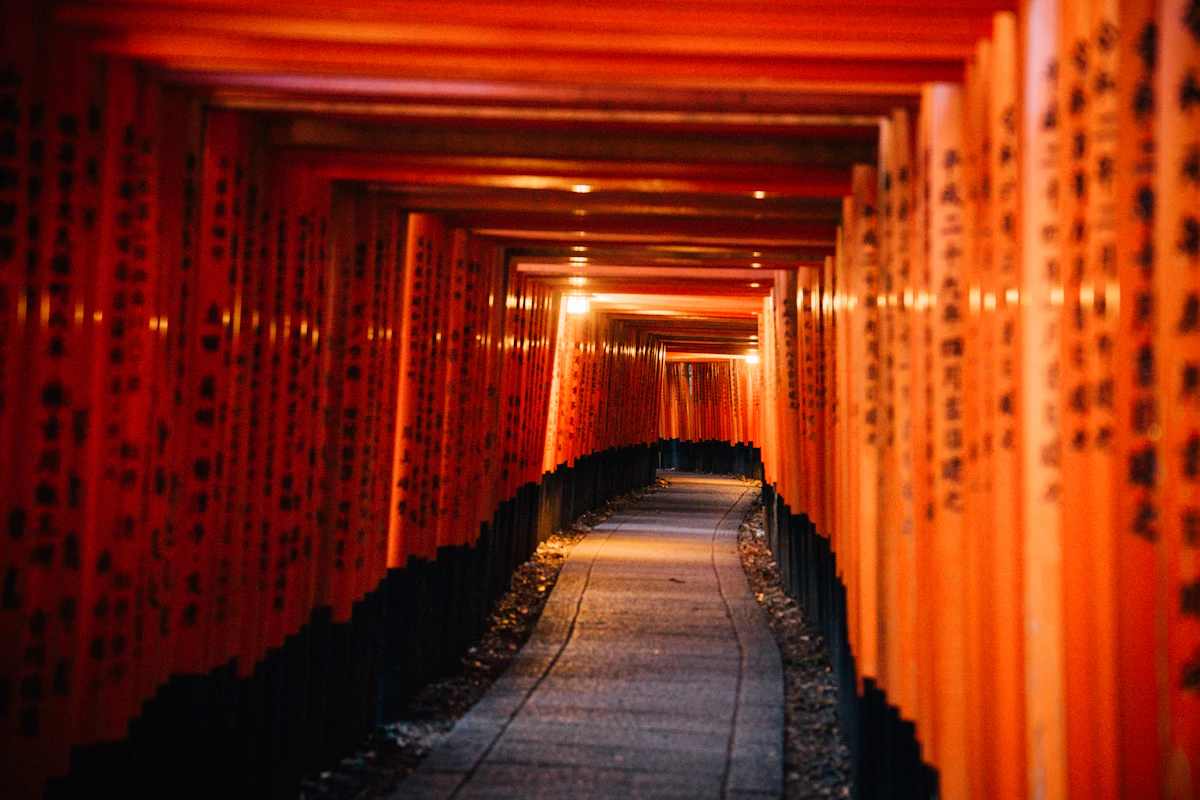 The vermillion torii tunnel at Nezu Shrine Tokyo, a row of gates curving along a forested hillside path
