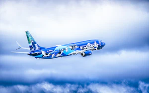 An Alaska Airlines jet climbing through clouds