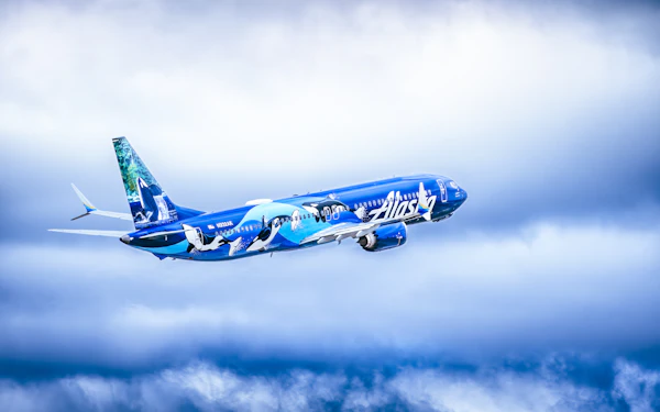 An Alaska Airlines Boeing 737 in its blue orca livery soaring through clouds &mdash; the new Atmos Rewards cards' up-to-80,000-point welcome bonus and who should actually apply