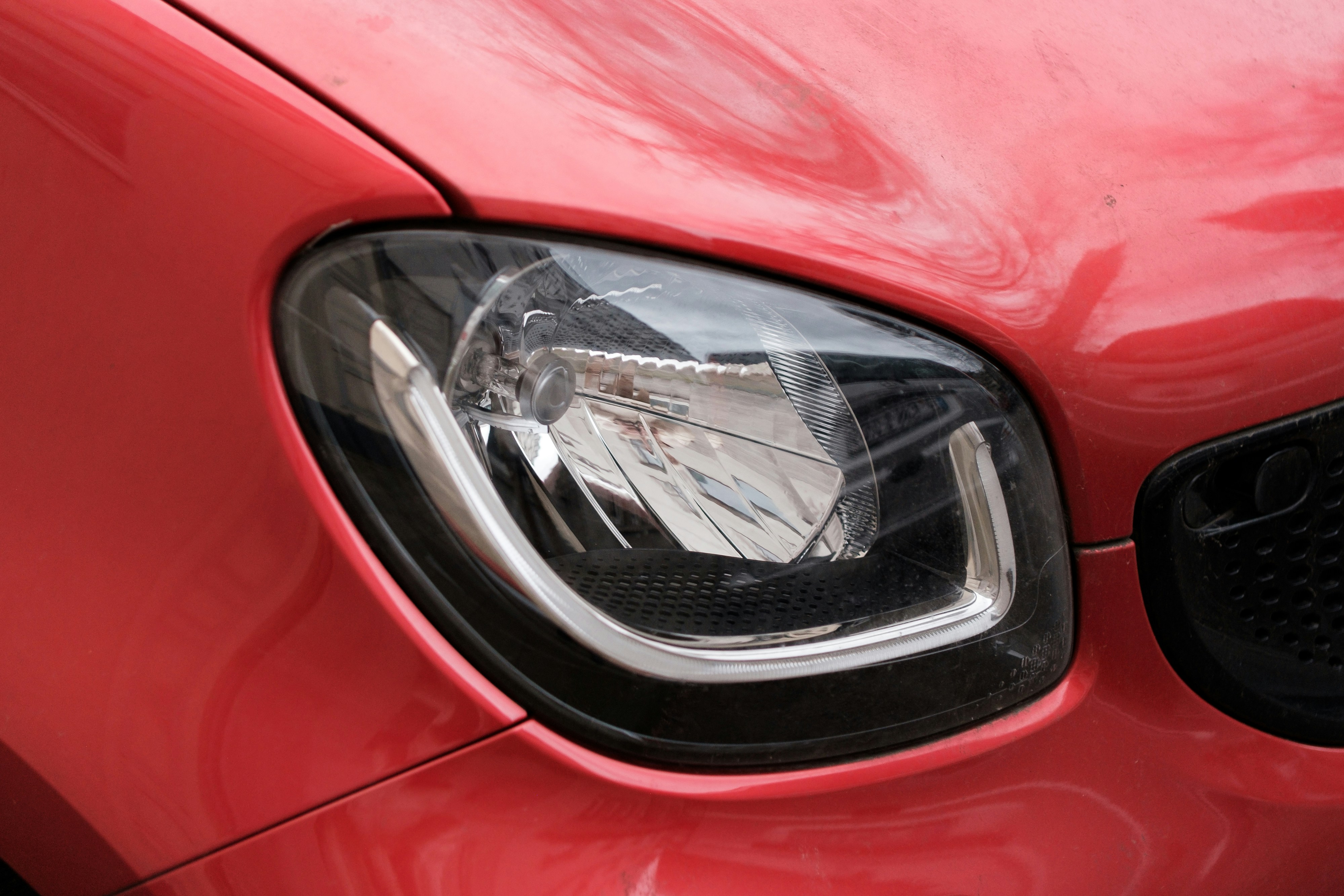 A red car's headlight is shown close up.